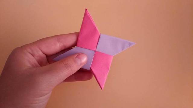 步骤17：接着反过来，紫色的纸也是同样的步骤对折把角塞到玫红色的纸里，最后折完后整理下就是下图的样子，基本已经做好了，但是还剩最后一步