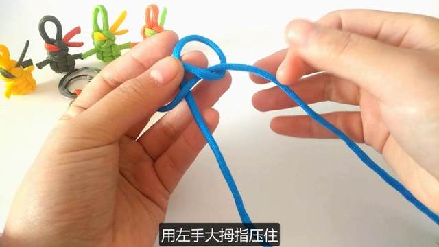 步骤2：然后开始来打纽扣结，首先把右边的绳子绕一个圈，然后反向压在左手大拇指下，绳子的绕圈方向注意看图片哦
