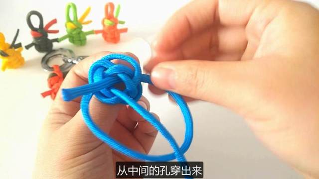 步骤10：接着把左边的绳子从右边绳子的底下绕过，同样从中间的孔穿到前面来