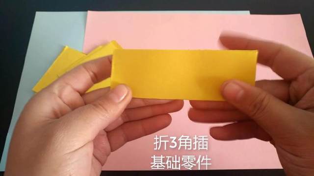 步骤3：取一张小长方形，开始做三角插的最基本部件，折成一个小三角，具体步骤，先把纸张横向对折一次