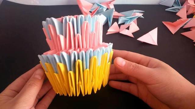 步骤19：然后把蛋糕的第一层和第二层组合在一起，组合的时候跟前面差不多，把第一层底下的粉色的纸条插进第二层顶端粉色的纸条里面