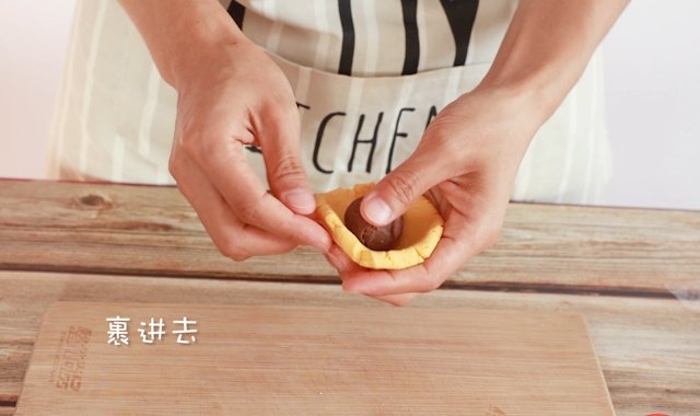 将一颗红豆夹心圆子包进南瓜糯米外皮中，揉圆封口。