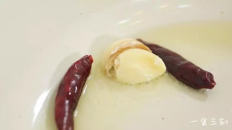 热油起锅，倒入蒜瓣、干辣椒爆香