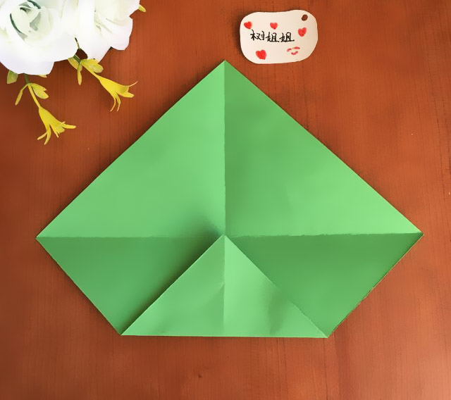 步骤2：将底部直角向中心点平行对折，形成一个小的等腰直角三角形，压实折痕，然后将折痕打开。
