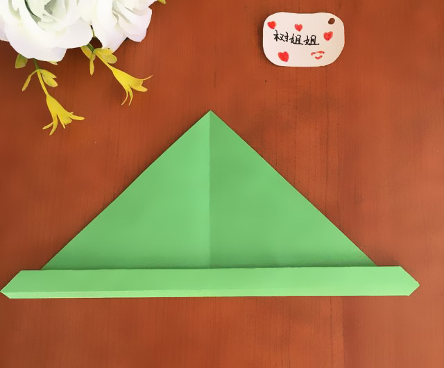 步骤5：将图4的边一直向上卷折，直到越过横向的中间线，如图所示。  注：在卷折的过程中，因为厚度会增加，所以最后折纸折完后，会超过中间线的位置，这属于正常现象。