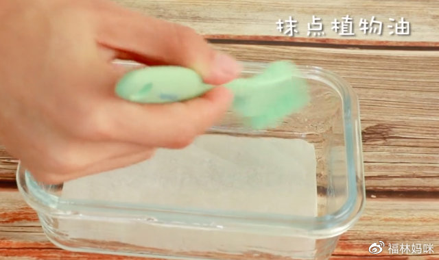 取一个干净的碗，底部放上硅油纸，四周抹点植物油，将搅拌好的南瓜糊倒入碗中。硅油纸和植物油可以方便蒸好的蛋黄南瓜糕脱模。