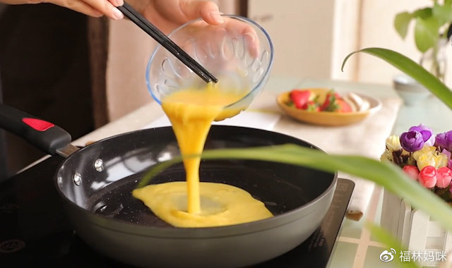 第3步：锅中倒入适量食油，在碗中磕入两个鸡蛋，打散后倒入锅中，将鸡蛋液均匀的摊在锅底。