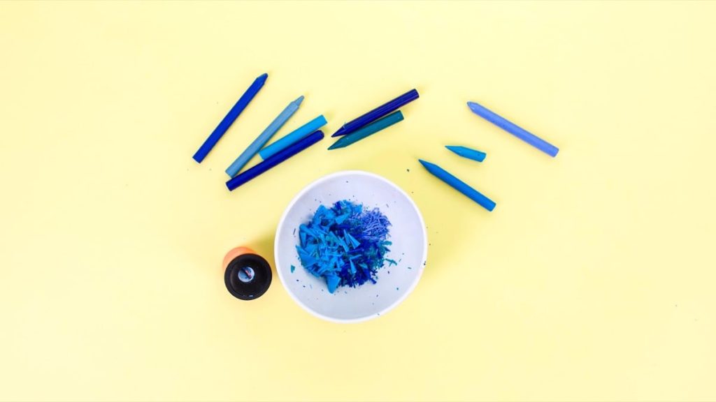 步骤3：将蜡笔预先浸泡在一碗水中，除去外层纸标签。除去标签后，使用铅笔刀将蜡笔磨碎成刨花。