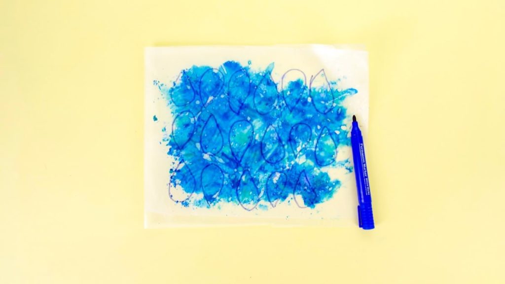 步骤7：使用蓝色记号笔在蜡纸上绘制雨滴形状并将其剪出。