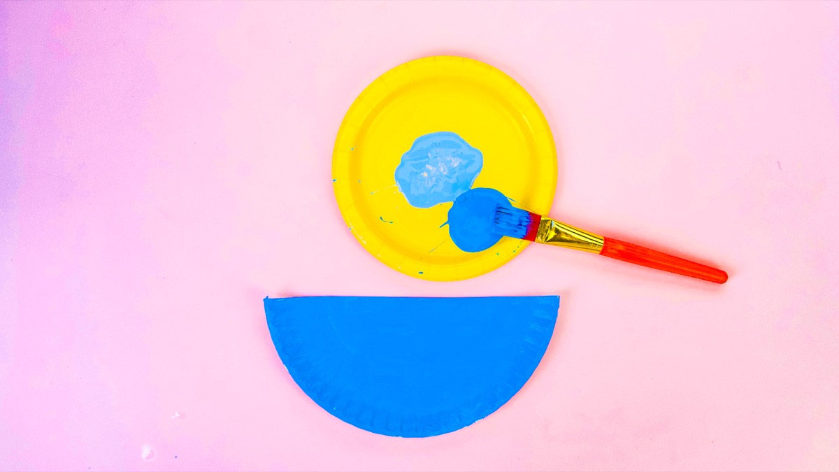 步骤3：为了让鸭子可以游泳，请把第二张纸盘切成两半，然后涂上深色的蓝色。将两块板放在一边干燥。