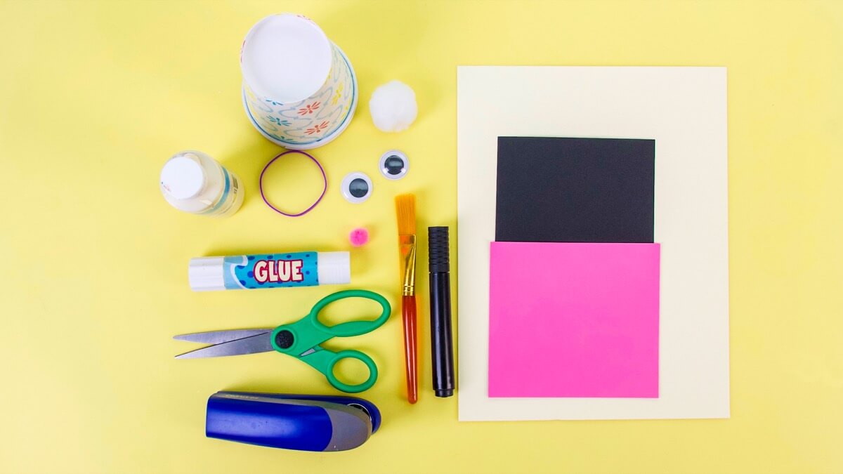 步骤1：工具准备：2个纸杯、颜料(兔子色)、卡纸(兔子色)、小块黑色卡纸、小块的粉红色卡纸、白色绒球或棉球、笔刷、眼睛(没有的话可以用卡纸制作)、胶棒、记号笔、剪刀、订书机、橡皮筋