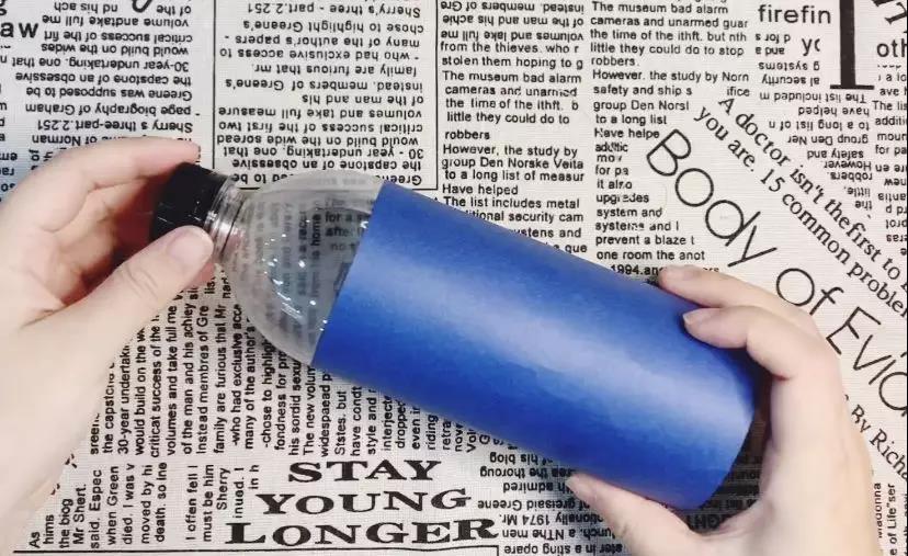 步骤1：用蓝色卡纸包裹住空矿泉水瓶三分之二，并粘贴。