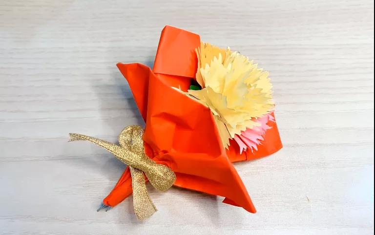 步骤10：做好三朵康乃馨后，用红色卡纸束在一起，再用蝴蝶结装饰，这样一束美丽的康乃馨就做好啦！