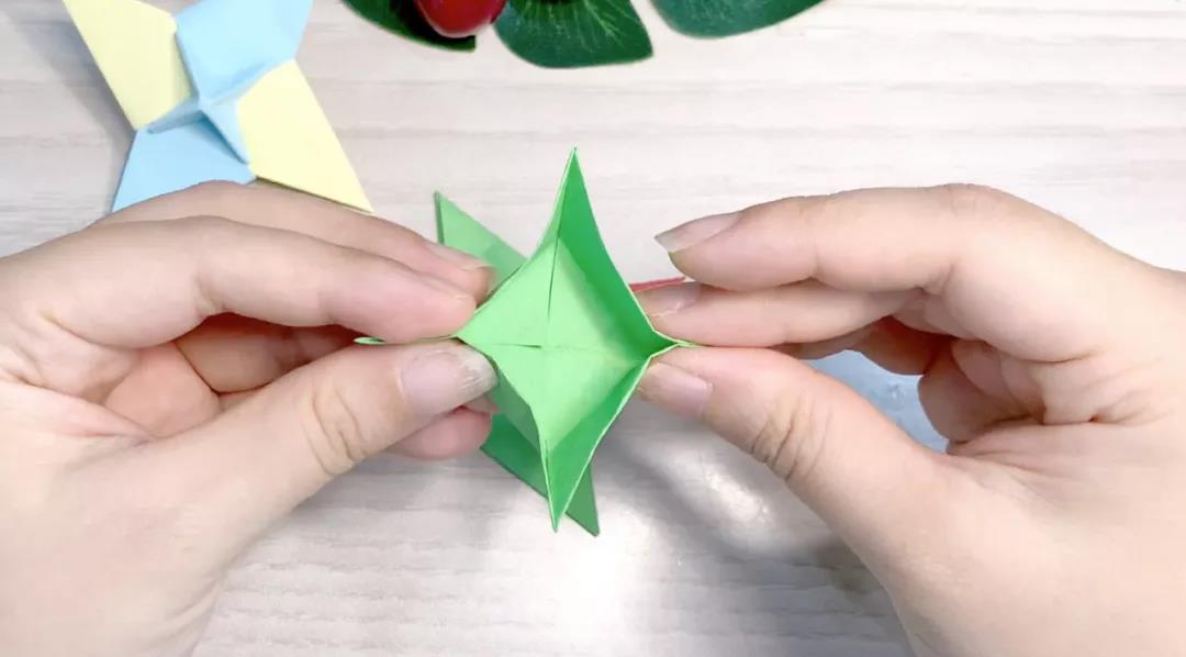 步骤13：展开后捏住四边的角，沿刚才的折痕折出风车状。