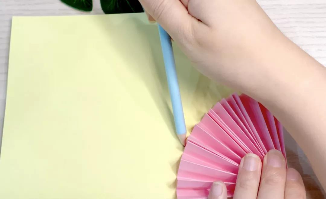 步骤17：黄色卡纸对折后闭口在底部，将扇形放在右下角勾出轮廓后剪下。