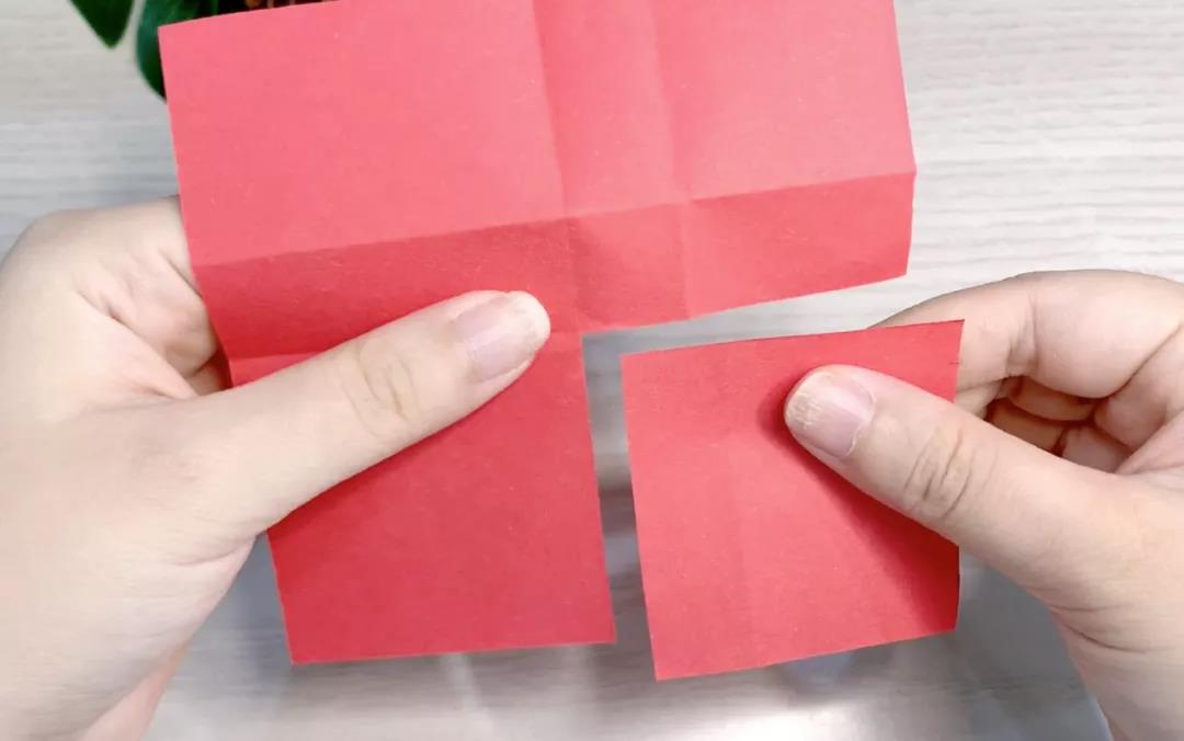 步骤19：正方形的红色卡纸对折成田字形后，剪下一个小正方形。