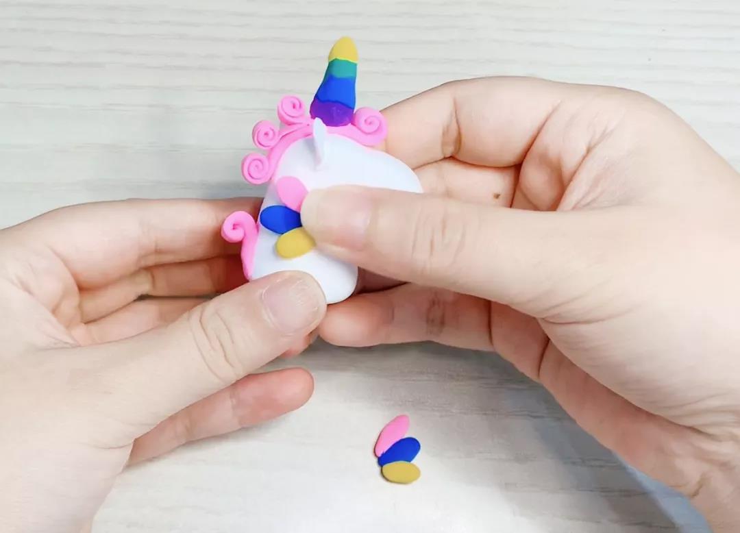 步骤12：取三块不同颜色的黏土，搓成不同大小的小圆柱形，合在一起做成翅膀，并粘在两侧。