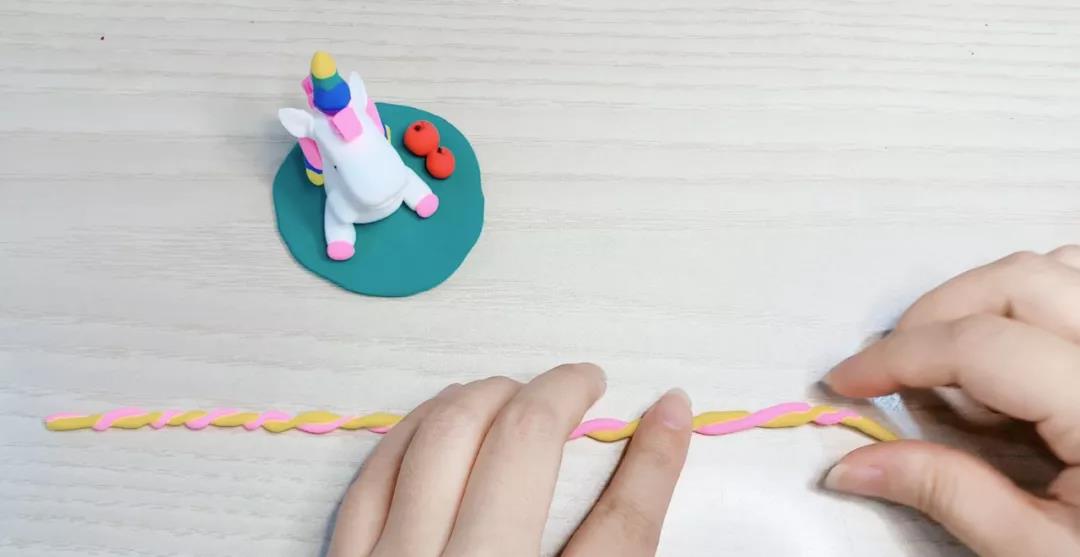 步骤18：将两个不同颜色的黏土搓成长条交叠在一起成麻花状。