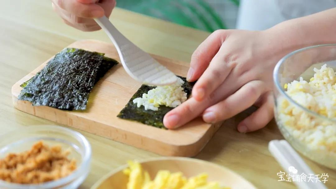 把适量的米饭平铺在海苔片上，稍微压实一下