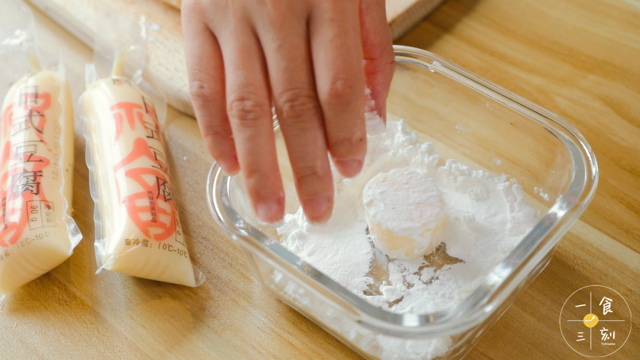 把切开的日本豆腐放到在玉米淀粉中滚一滚，让表面均匀地裹上玉米淀粉