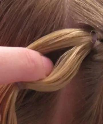 取这束发束的第二段，用皮筋扎住，在中间将头发分开，如图