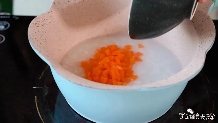 米粥在锅里烧开，倒入胡萝卜碎煮软