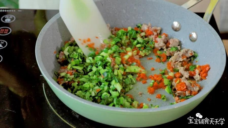 锅里倒油，小火加热，倒入胡萝卜、油菜粒和牛肉肉糜翻炒炒软炒熟