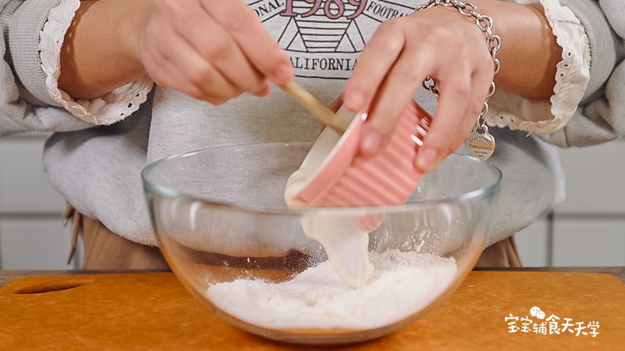 让糯米粉中倒入炼奶水，边倒边搅拌成棉絮状