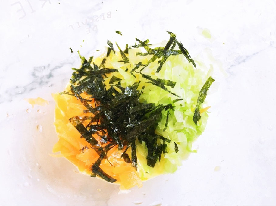 放入切好的包菜丝和胡萝卜丝，再用剪刀将海苔剪碎一起放进去。