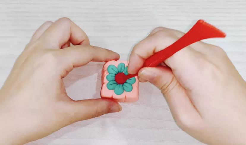 步骤10：搓一个红色的圆球在中心，用工具戳出一些洞洞。