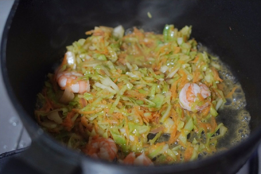 第7步：加入能铺平锅底的清水，翻炒，小火煮1分钟左右，将虾仁和蔬菜炒熟。