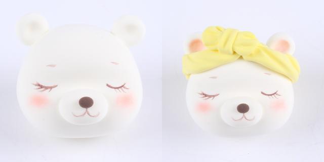 步骤5：白色粘土做出耳朵粘好，耳窝里涂上粉红色色粉，用黄色粘土做一根蝴蝶结发带戴在小白熊头上。