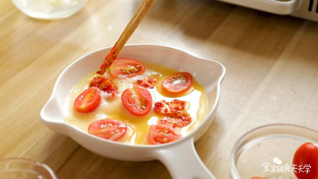 把煎好的番茄鱼肉肠放入蛋液中，再铺上小番茄