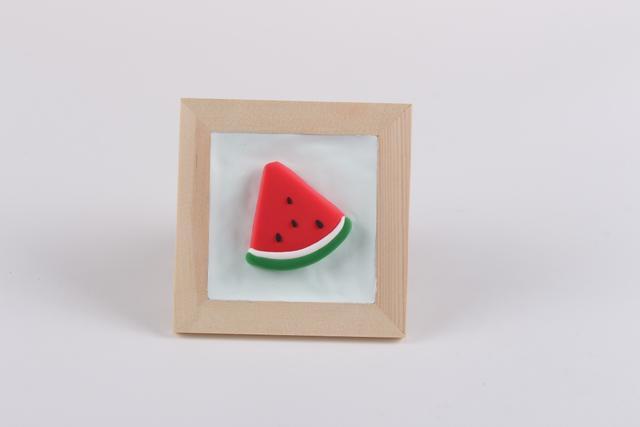 步骤6：黑色粘土做出西瓜籽粘在西瓜上，这样西瓜粘土画就做好了。