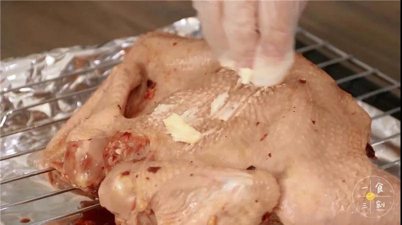 用软化黄油涂抹鸡的表面，撒上一点黑胡椒