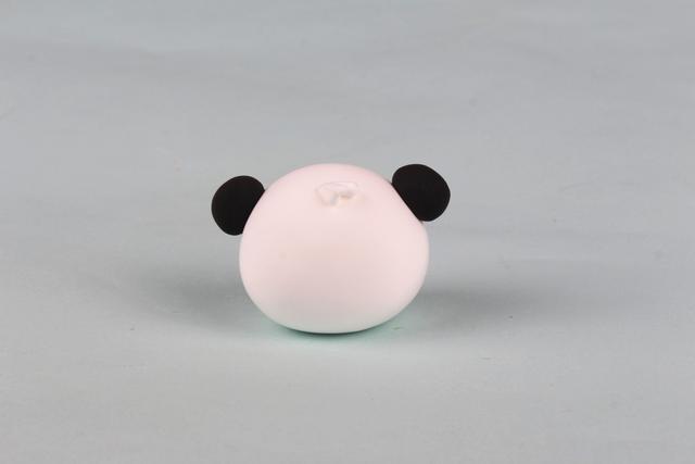 步骤2：黑色粘土做出熊猫的两只耳朵粘上，白色粘土做三根头发粘在头上。