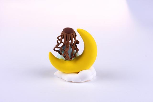 步骤10：下面开始做女孩的头发，用深褐色粘土切细条然后弯曲成烫发的效果，一根一根的粘在后脑上上，如图所示，这是第一层头发。