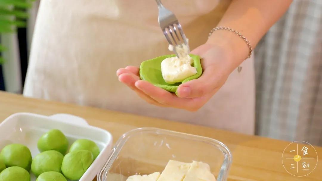 第10步：取一个面团，用掌心压扁，慢慢揉成小碗状，放入鲜奶馅，捏圆