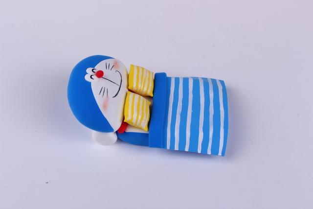 步骤8：用丙烯颜料给被子和枕头画上条纹作为装饰，哆啦A梦涂上腮红，这样蓝胖子的小床就做好啦！