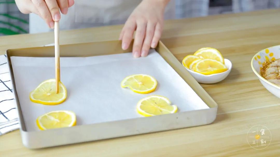 在烤盘铺一张烘焙纸，平铺上柠檬片，烤箱预热180度