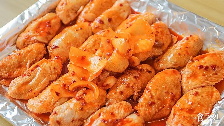 第6步：第二天从密封袋中取出鸡翅，整齐排列在铺着锡纸的烤盘上，淋上酱汁，别忘了把洋葱也铺上去
