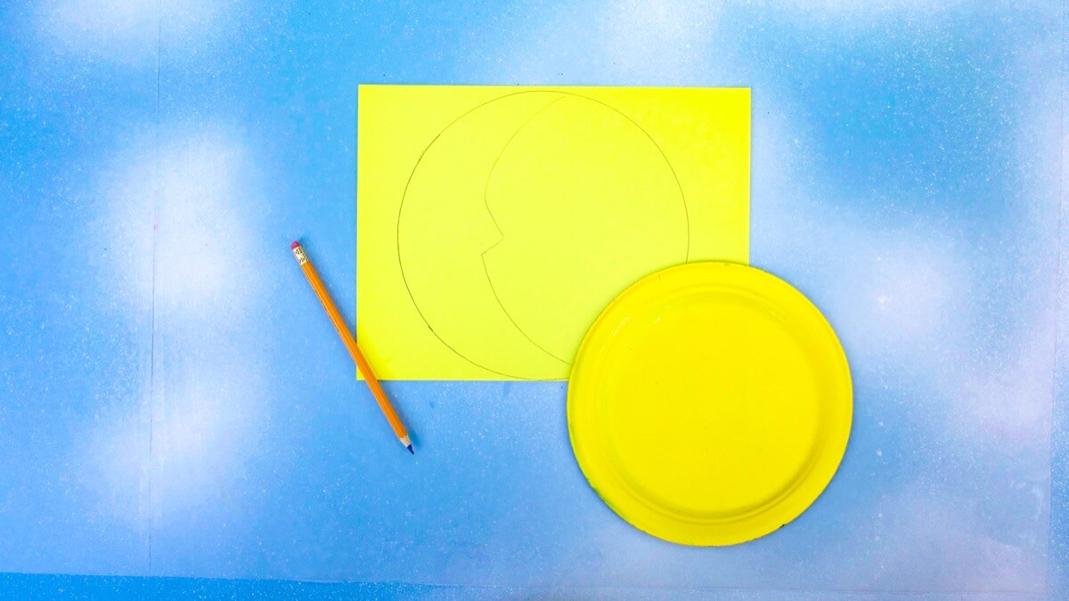 步骤4：在黄色纸上画出纸碟的轮廓。在圆内画一个新月形，在中心画一个小鼻子轮廓，成为月亮。