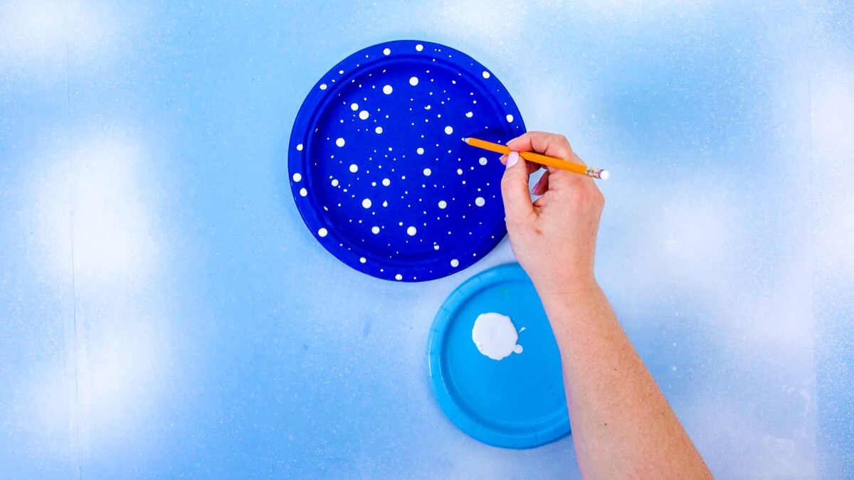 步骤7：在盘子的蓝色面上画星星–将铅笔的两端浸入白色涂料中，并在盘子上点缀，添加任意数量的星星。晾干。