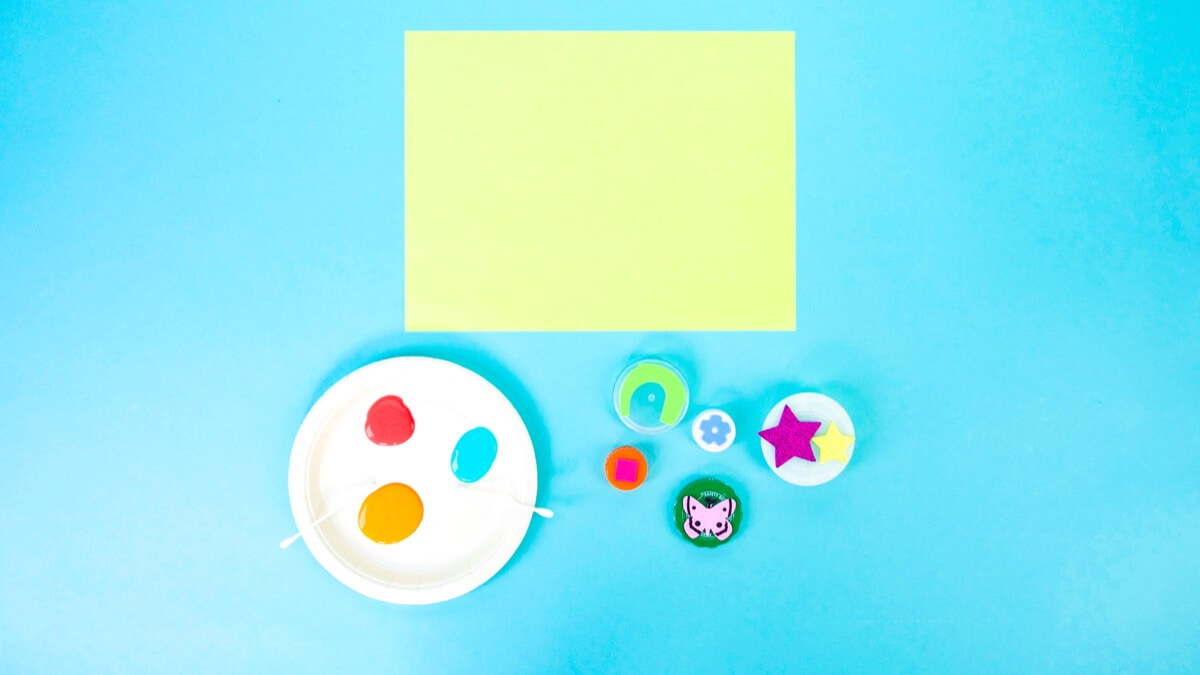 步骤2：选择一张彩纸作为风筝的底座。在纸碟上准备一些深浅的颜料。