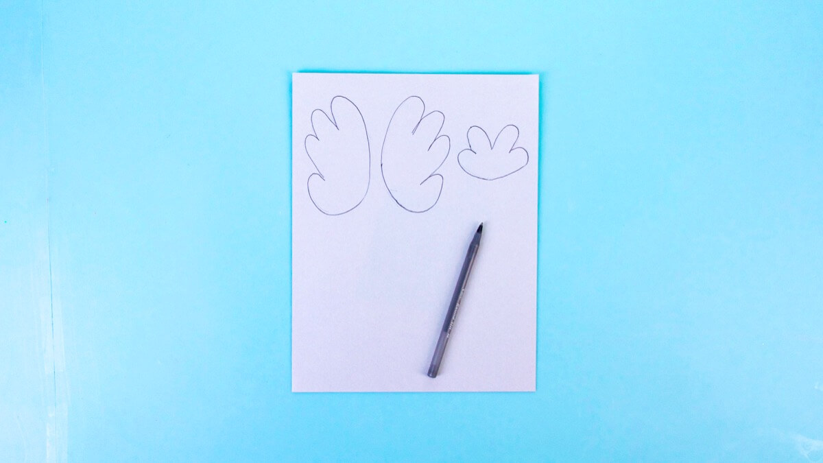 步骤3：接下来，通过在灰色的纸上画出翅膀剪出来制作一些翅膀和尾巴。