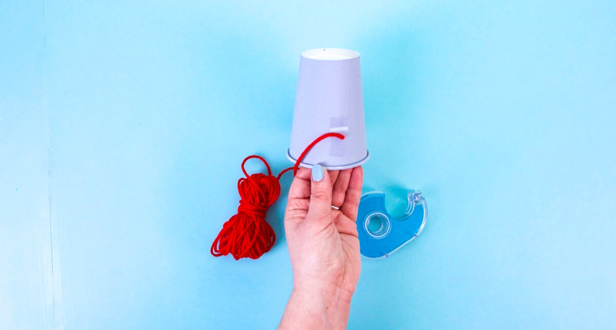 步骤5：在身体底部附近使用一块双面胶带。这将是您的红色毛线的锚点。开始在杯子的底部缠绕毛线，以使知更鸟的肚子变红。完成缠绕后，在末端添加一些白胶并修剪。