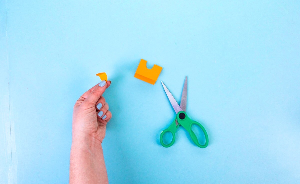 步骤8：使用一小块对折的橙色彩纸修剪出椭圆形。这将是喙。