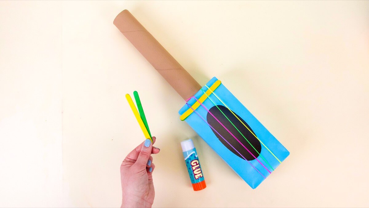 步骤5：通过在盒子周围拉伸来添加琴弦，并尽可能地将它们移到吉他琴体的开口中。