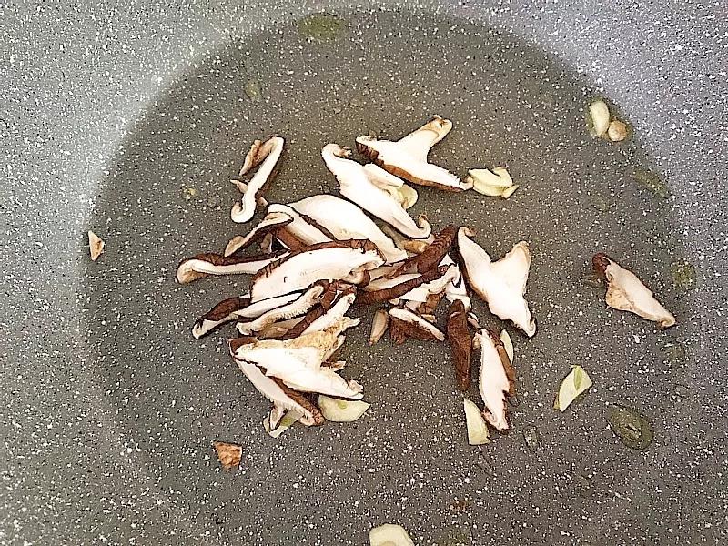 大蒜片放入油锅炒香后，香菇放入锅中翻炒。