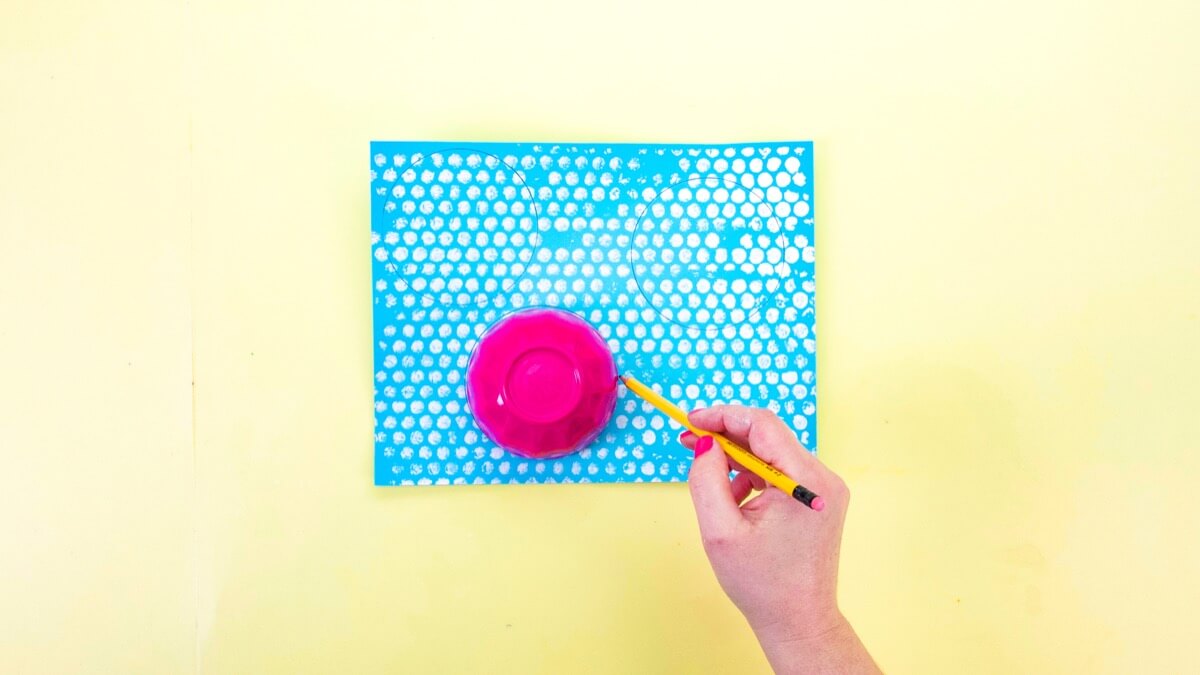 步骤3：油漆干燥后，使用杯子或任何其他圆形的家用物品在蓝色卡片纸上画三个圆圈，然后用剪刀剪下来。